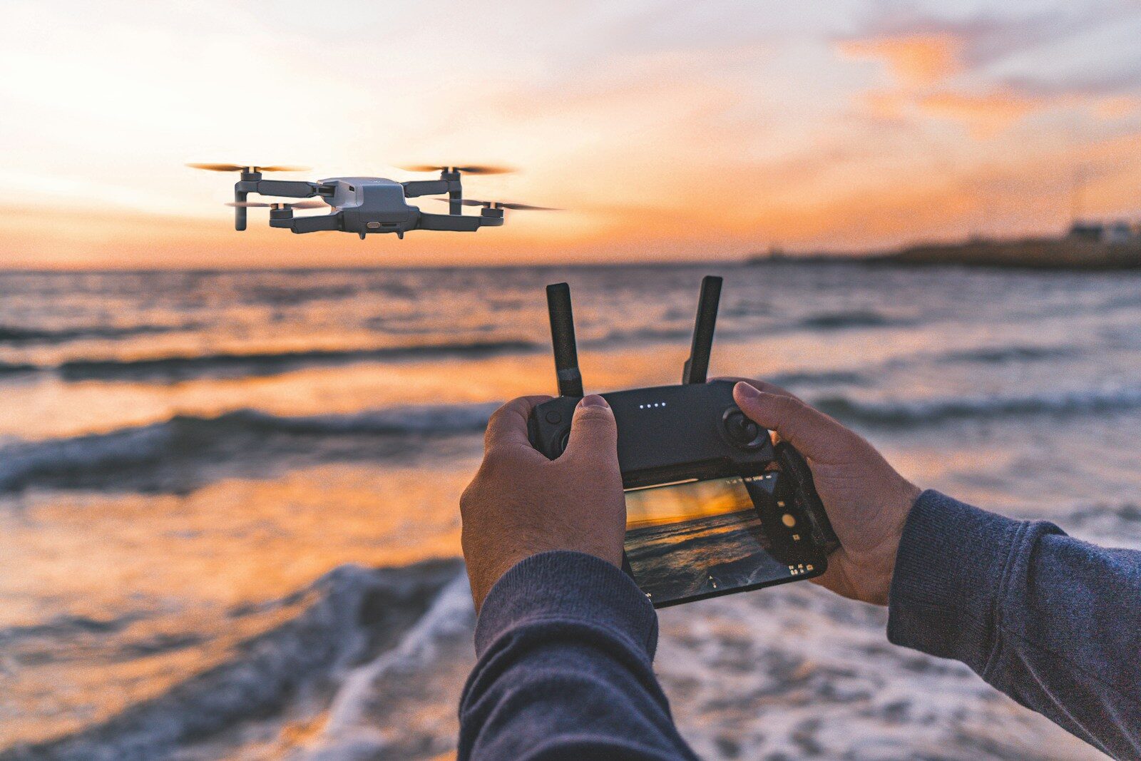 Photo by Hc Digital person operating drone flying above seashore